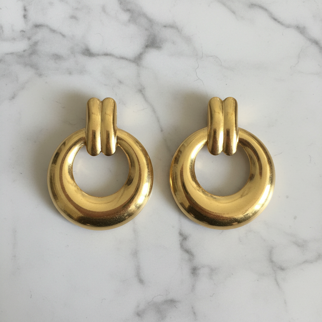 Gold door knocker earrings on marble